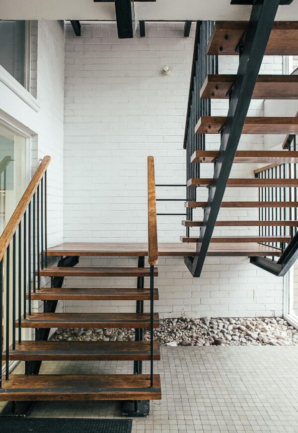 Black stairway with wooden railings of residential building placed on terrace with white brick wall of modern house