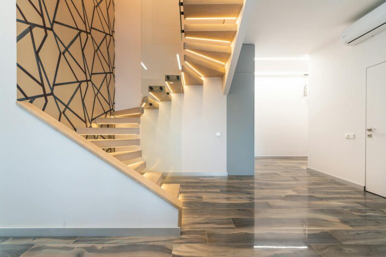 Contemporary hall interior with door against curved staircase and wall with geometric ornament in light house